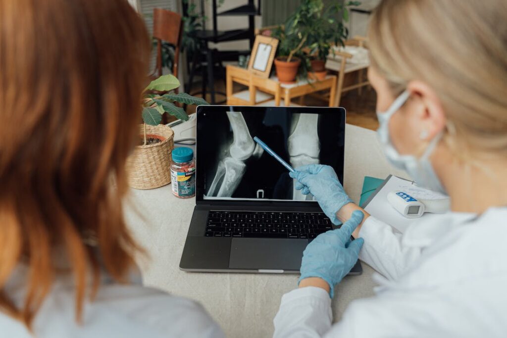 two professionals are looking over medical imaging on a laptop